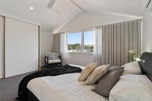 um quarto com uma cama com almofadas e uma janela em 13 47-48 Franklin Pde - Linen Included - Waterfront em Encounter Bay