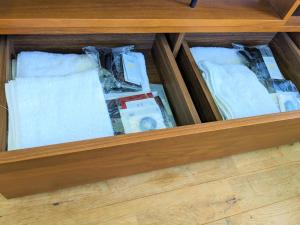 a wooden drawer with white towels in it at B&BHOUSE FAM in Ichinomiya