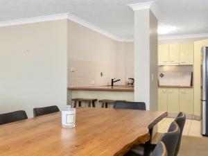a kitchen and dining room with a wooden table and chairs at Beachfront On Marine in Kingscliff