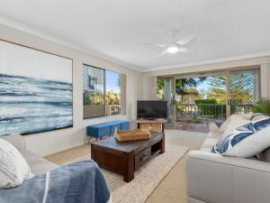 a living room with a couch and a tv at Beachfront On Marine in Kingscliff