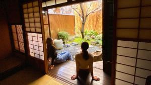 two women sitting on a porch looking at a garden at Guesthouse Kioto in Kyoto
