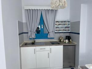 una cucina con armadi bianchi e una finestra blu di GIAVASI SEASIDE FINIKI a Foiníkion