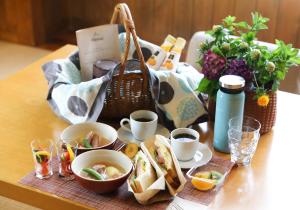un tavolo ricoperto di ciotole di cibo e un cesto di cibo di Sora no Mori Hotel Hanagori a Muraoka