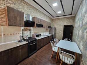 Il comprend une cuisine équipée d'une cuisinière et d'une table avec des chaises. dans l'établissement Новая 3-х комнатная квартира Мечта, à Boukhara