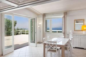 a white dining room with a table and views of the ocean at Villa Roby-Loft a Torri del Benaco in Torri del Benaco