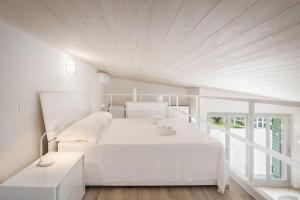 a white bedroom with a white bed and a window at Villa Roby-Loft a Torri del Benaco in Torri del Benaco