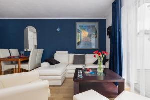 a living room with a white couch and a blue wall at Resort Kropli Bałtyku Apartments by Renters in Darłowo
