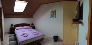 a small bedroom with a purple bed with a skylight at Guesthouse Magdalena in Rakovica