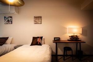 楓ホテル302 في أوساكا: غرفة بسريرين ومكتب فيه مصباح
