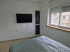 een slaapkamer met een bed en een flatscreen-tv aan de muur bij Abi's perfect place in Jeruzalem