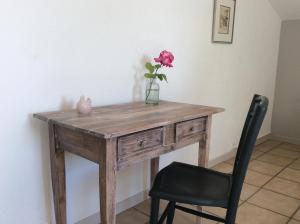 una mesa de madera con un jarrón con una flor. en Le Clos du Plantis en Sonnac