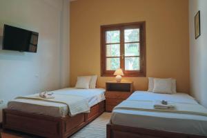 1 dormitorio con 2 camas, TV y ventana en VILLA GEOLENA, en Agios Georgios Nilias