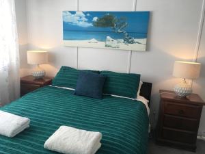 ein Schlafzimmer mit einem grünen Bett mit zwei Lampen in der Unterkunft SHELLHARBOUR BEACH COTTAGE ---- Back gate onto Beach, Front gate walk to Marina in Shellharbour