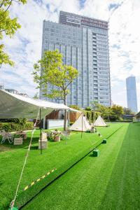 una tienda en un campo de hierba con un edificio alto en The Westin Shenzhen Nanshan en Shenzhen