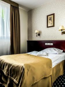 a hotel room with a bed with a gold blanket at Hotel Adria in Ruda Śląska