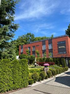 a red brick hotel with bushes in front of it at Hotel Adria in Ruda Śląska