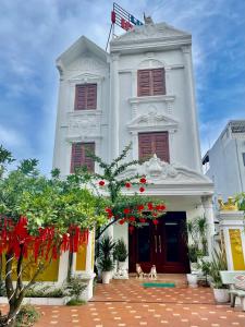 Um edifício branco com dois cães à frente. em Luxury Hotel T&L em Cẩm Phả