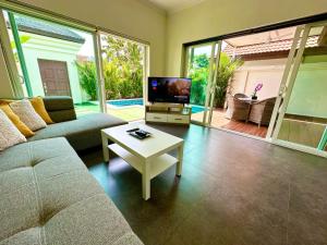 - un salon avec un canapé, une télévision et une table dans l'établissement View Talay Villas - Luxury 1BR pool villa nr beach - VTV 170, à Jomtien Beach