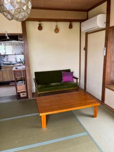 a living room with a green couch and a table at Guesthouse Papaya in Shimoda