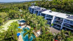an aerial view of a resort with a pool and palm trees at The Oasis Apartments and Treetop Houses in Byron Bay