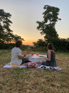 Un uomo e una donna seduti ad un tavolo da picnic sull'erba di Casa Olea a Montarice