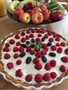 a fruit pie on a table with a plate of fruit at Pod Różą in Łeba