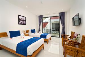 a hotel room with two beds and a television at Legend Charm Boutique Hoi An Hotel in Hoi An