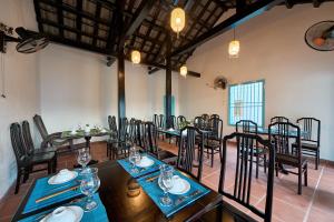 a restaurant with tables and chairs in a room at Legend Charm Boutique Hoi An Hotel in Hoi An