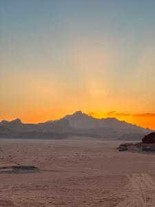 a sunset in the desert with mountains in the background at Tareqzwy wadi rum in Wadi Rum