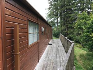 een houten promenade die leidt naar een hut met een raam bij Snowdonia Holiday Lodges in Beddgelert
