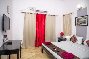 a bedroom with a bed with red curtains and a desk at RONNE'S VILLA De SOL-3BHK LUXURY VILLA In Assagaon in Mapusa