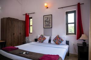 una camera da letto con un letto bianco con tende rosse di RONNE'S VILLA De SOL-3BHK LUXURY VILLA In Assagaon a Mapusa