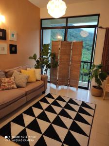 sala de estar con sofá y ventana grande en Jean CleanComfy Apt Near Beach, en Batu Ferringhi