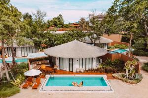 an overhead view of a woman swimming in a swimming pool at VALA Hua Hin - Nu Chapter Hotels in Cha Am