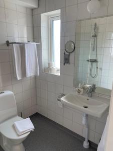 een badkamer met een wastafel, een toilet en een spiegel bij Bedinge Golfklubb hotell in Beddinge Strand