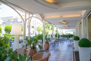 un vestíbulo con mesas, sillas y plantas en Hotel Darsena, en Riccione