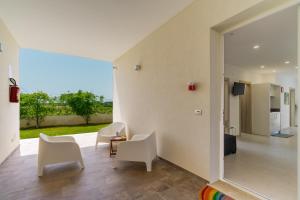 a living room with white chairs and a large mirror at Le scuderie 6 in Galatone