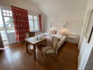 a room with a table and a bed and a table and chairs at Villa Pension Strandhaus - adults only in Travemünde