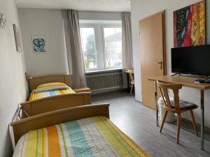 a bedroom with two beds and a desk and a computer at Hotel Roma in Merzig