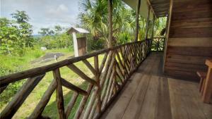 a wooden porch of a house with a view of a field at Rainforest Hut in Archidona