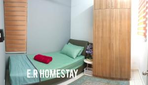 a small room with a green bed with a red pillow at ER Homestay for Family Transit Nearby KLIA in Sepang