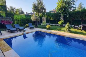 una piscina en un patio con 2 sillas azules y un patio en Villa Koral in Kirkpinar - Sapanca, en Sapanca