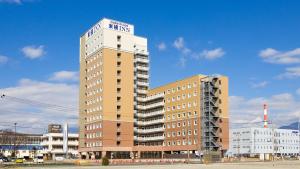 富士市东横INN新富士站南口(Toyoko Inn Shin-fuji-eki Minami-guchi)的一座高楼，楼顶有标志