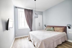 a white bedroom with a bed and a window at Cosy 3 room apartment. in Vilnius