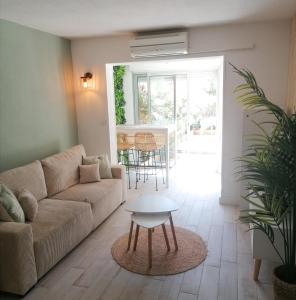 a living room with a couch and a table at Appartement Zen à Frejus avec jardin, piscine, tennis, proche mer in Fréjus