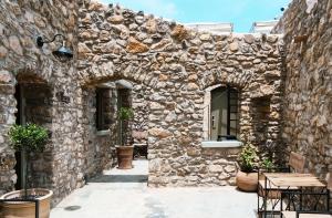 um edifício de pedra com arcos, uma mesa e cadeiras em Pyrgi Cretan Living & Spa em Pírgos