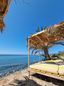 a beach with a straw umbrella and the ocean at Summer Dream Cyprus in Maroni