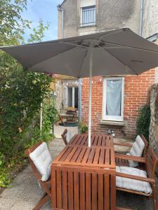 a wooden table with an umbrella on a patio at Logement de charme à Azay le Rideau in Cheillé