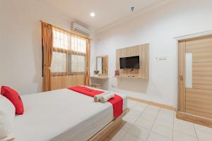 - une chambre avec un grand lit et une télévision dans l'établissement RedDoorz Syariah near Taman Bekapai 2, à Klandasan Kecil