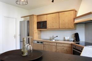a kitchen with wooden cabinets and a table with wine bottles at Felsen Apartment Loft in Engen